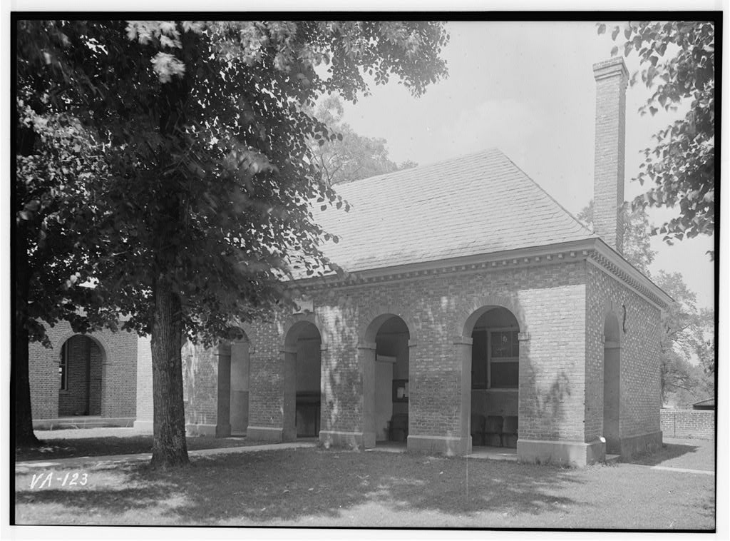 Archival photograph of King William County Courthouse, with its brick arcade and a tree in the foreground.