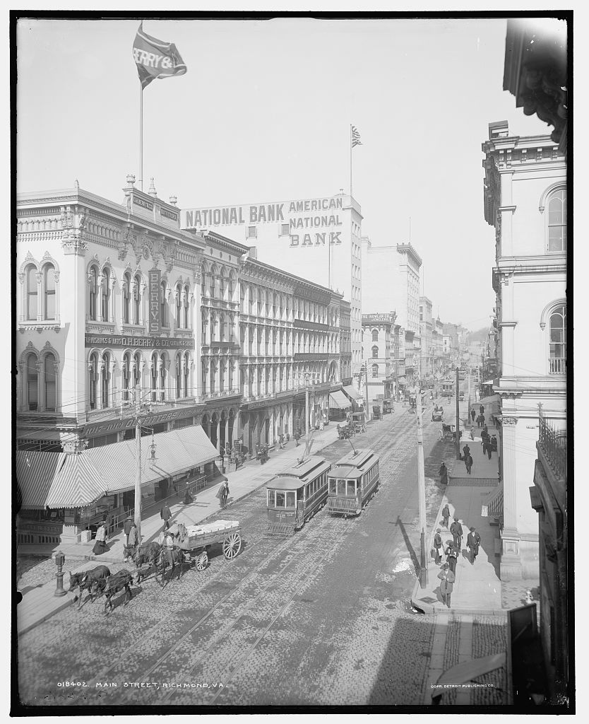 Historic Richmond street scene with shops, pedestrians, and streetcars.